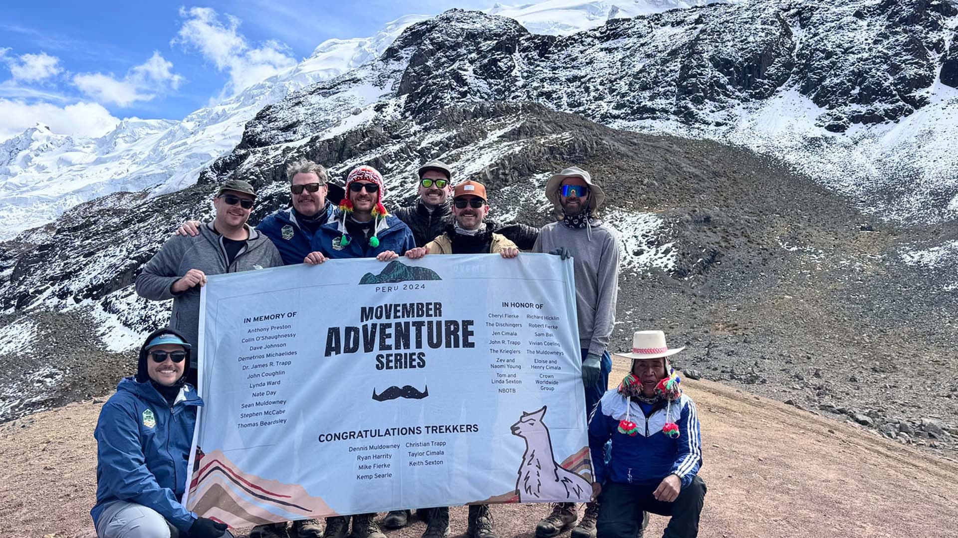 Photo of Movember supporters holding a Movember sign near the peak of a Peruvian mountain
