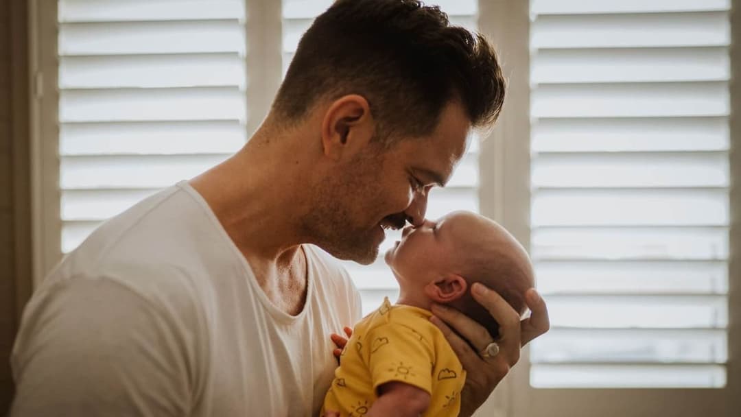 a man holding his baby and smiling