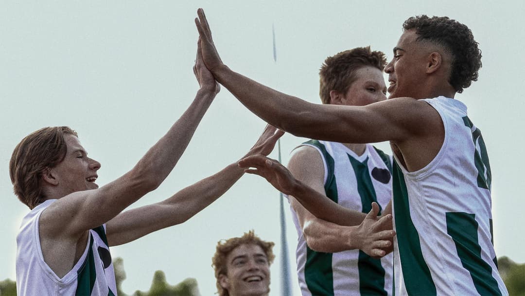 Two young male football players high-fiving.