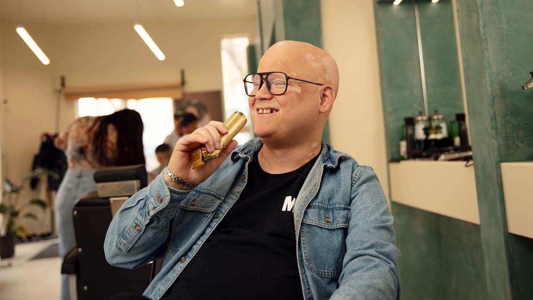 L’humoriste Simon Delisle prend la pose dans un fauteuil de barbier, tenant un rasoir électrique comme s’il s’agissait de son micro