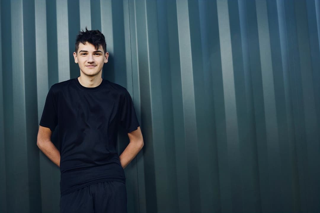 A young male leaning up against a metal wall