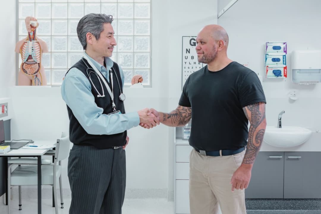 Young man in doctor's white coat speaking to someone