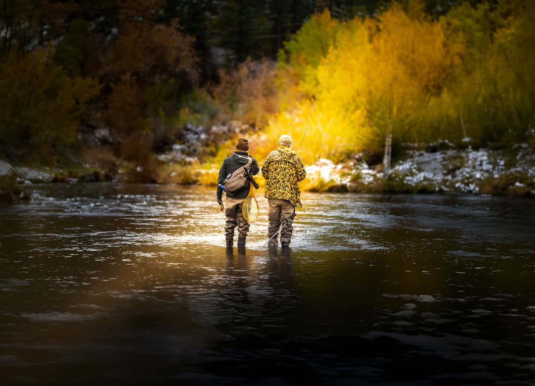 Two men standing side by side in a shallow river