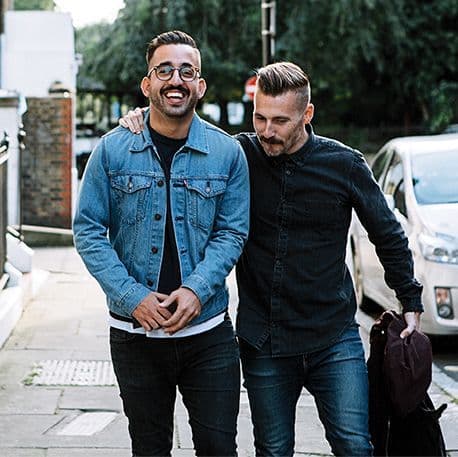 Two men smiling, one has their arm around the other