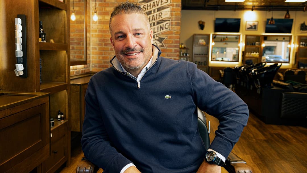Un Mo Bro souriant est assis dans un fauteuil de barbier d’un salon de coiffure à Calgary