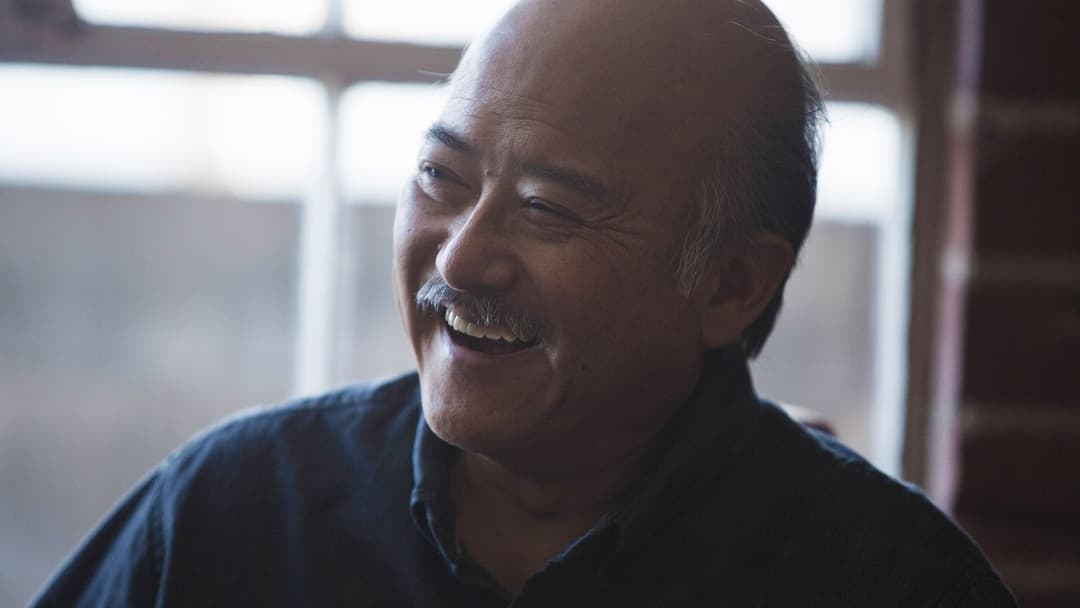 A candid photo of a moustachioed man laughing