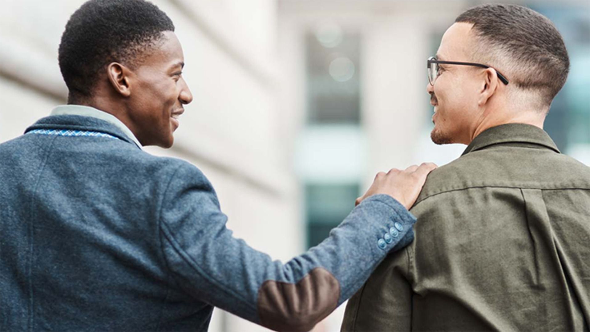 Photo of two men cheerfully walking down the street.