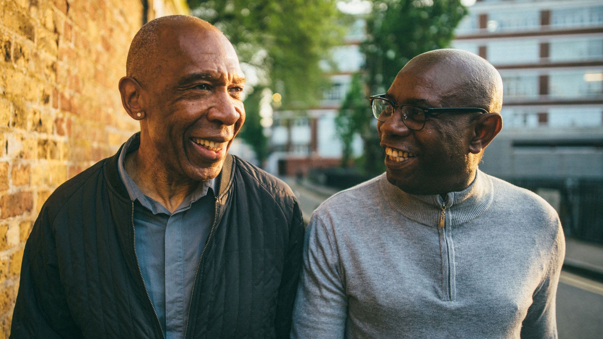 Photo of two smiling middle-aged men walking down a street.